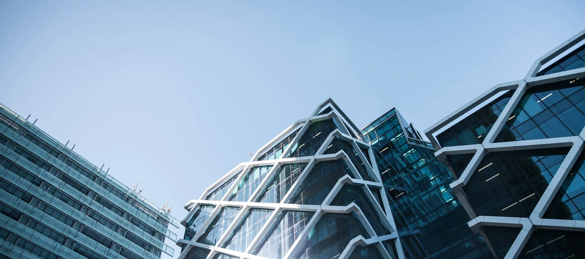 The angular glass and white frame of a modern city building against a clear sky