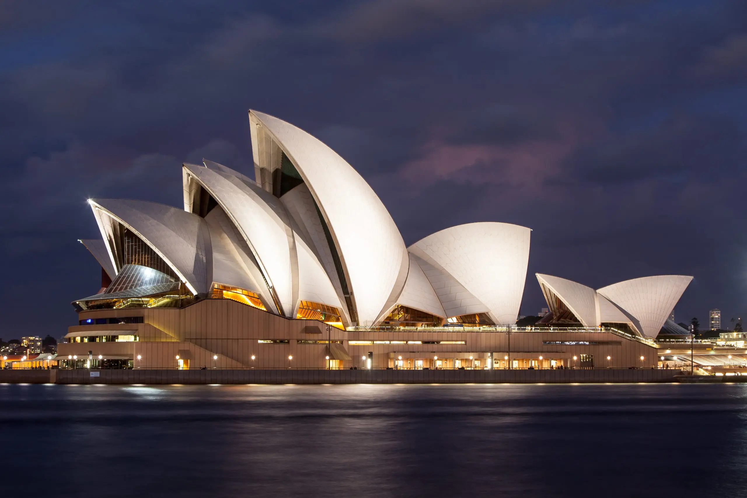 The Sydney Opera House lit at dusk across the harbour